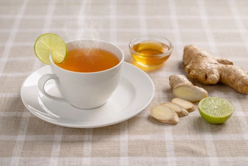 Taza de agua de kión con rodajas de jengibre fresco, miel y limón